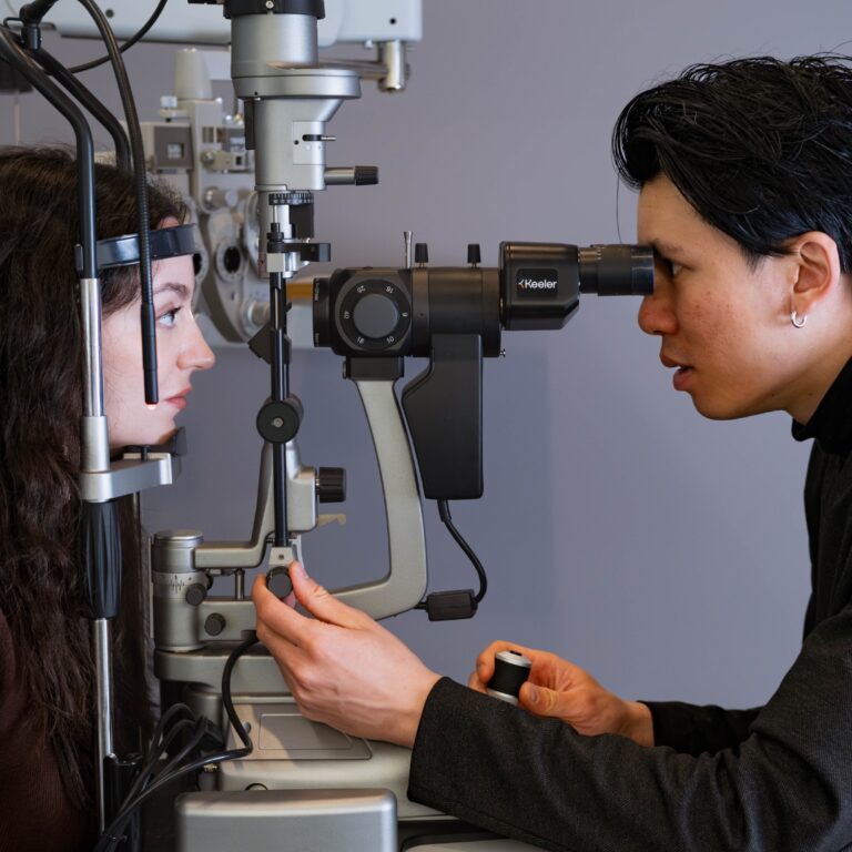 Optometrist examining a patient’s eyes using a slit-lamp microscope during a comprehensive eye examination.